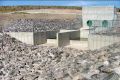 Concrete-lined plunge basin with baffle wall, grouted riprap side slopes, and discharge channel. Flow discharges into the plunge basin from two 36-inch diameter fixed-cone valve.