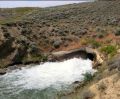 7.5-foot horseshoe conduit discharging into an outlet expansion with a depressed floor. Downstream channel armoring has also been provided.